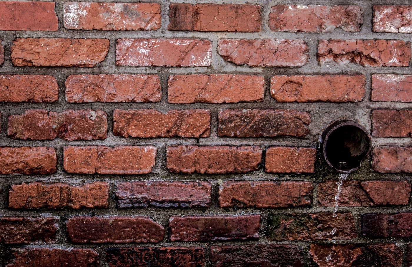 Eau qui ruisselle sur un mur en briques - infiltration causée par une étanchéité défaillante